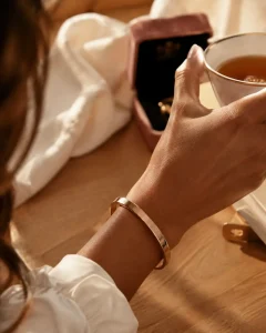 Bracelet rose or jonc en or rose sur poignet féminin, détail bijou