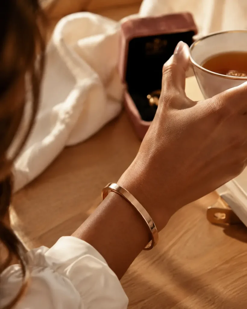 Bracelet rose or jonc en or rose sur poignet féminin, détail bijou